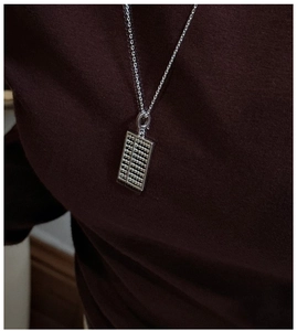 Détail d'un pendentif abaque en argent S925 sur fond de pull en maille rouge foncé