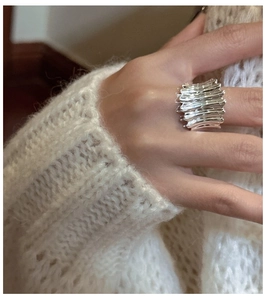 Détail d'une bague large en argent S925 avec texture ondulée portée sur un doigt de femme