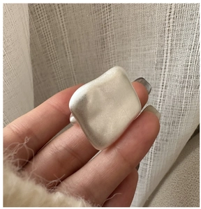 Close-up of matte S925 sterling silver square ring on hand with elegant fabric background