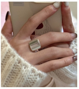 Bague carrée en argent sterling S925 poli sur un doigt avec un pull beige doux