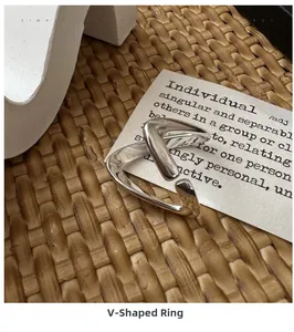 Détail d'une bague en argent minimaliste en forme de V sur un fond tissé texturé