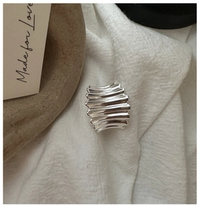 Gros plan d'une bague en argent S925 à texture ondulée sur un tissu blanc doux