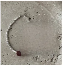 Detail of S925 silver beaded bracelet with red agate stone and heart charm on card