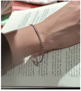 Close-up of S925 sterling silver beaded bracelet on wrist over a vintage book
