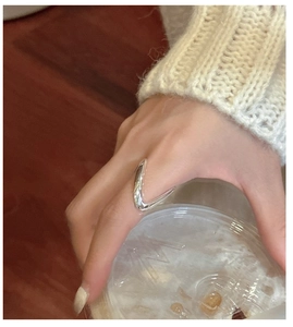 Gros plan d'une bague V minimaliste en argent au doigt montrant un fini poli