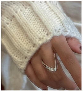 Détail d'une bague en V argentée polie de style minimaliste portée sur un doigt élégant