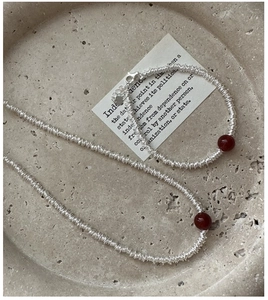 Macro detail of S925 silver coiled jewelry set with deep red agate stones on grey plate