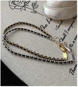 Detail view of woven beaded bracelets with silver and gold beads on a rustic linen backdrop