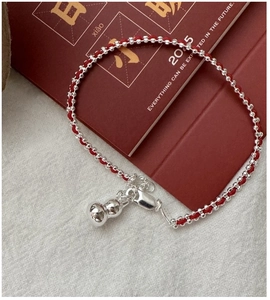 Detailed macro view of S925 sterling silver gourd charm on red braided rope bracelet