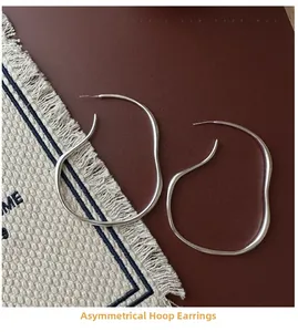 Detailed close-up of S925 sterling silver irregular wavy hoop earrings on a textured fabric