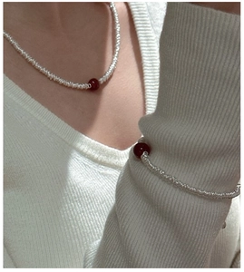 Close-up of minimalist S925 silver beaded necklace and bracelet set with red agate