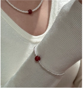 Detail of S925 silver beaded necklace and bracelet set with red agate on a model