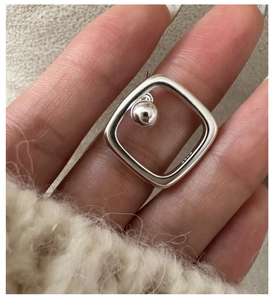Vista macro di orecchini geometrici quadrati in argento sterling S925 con sfera lucida