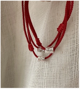Gros plan du bracelet corde tressée rouge avec trois perles en argent texturées