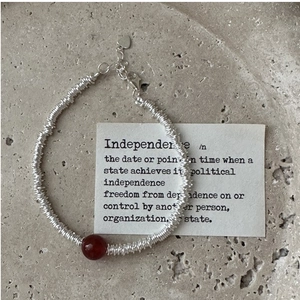 Macro detail of S925 sterling silver chain with red agate gemstone on a stone tray