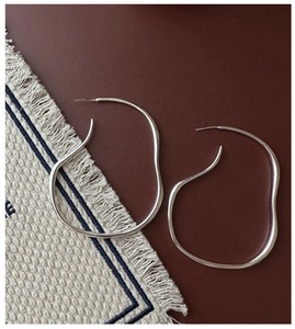 Detailed view of large S925 sterling silver irregular hoop earrings on a dark background