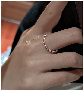 Dettaglio ravvicinato di un anello in corda rossa intrecciata con perle d'argento e ciondolo