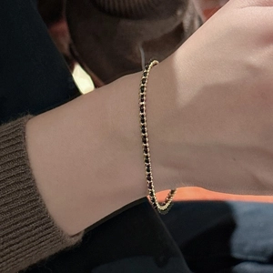 Elegant gold tennis bracelet with black spinel stones worn on a female wrist