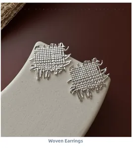 Macro view of woven textured S925 sterling silver square earrings on stone