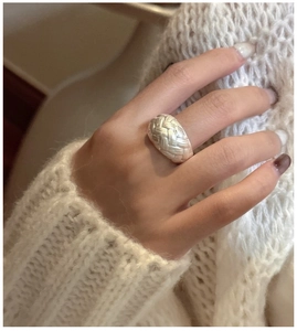 Macro shot of silver woven texture ring showcasing wide band and brushed metallic details