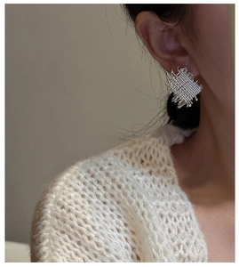 Detail view of woven S925 sterling silver square earrings worn on a female model