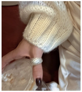 Detail shot of sterling silver woven wide ring paired with a white knit sweater