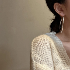Minimalist S925 sterling silver large irregular hoop earrings worn by a model in soft light