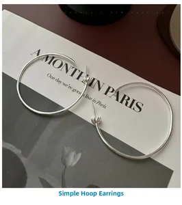 Gros plan de créoles minimalistes en argent S925 sur une page de magazine vintage