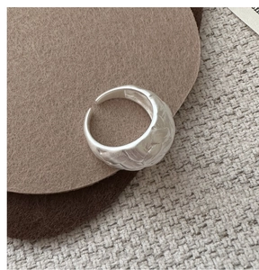 Macro shot of textured sterling silver ring with rustic hammered finish on a felt surface