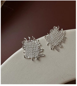 Macro shot of silver S925 earrings with woven texture and artistic fringe details