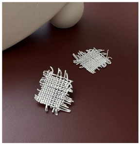 Macro side view of S925 sterling silver woven square earrings on dark red background