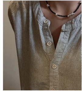 Détail du collier de pépites d'argent avec perles d'onyx noir sur chemise marron