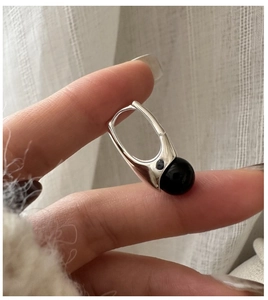 Macro shot of S925 sterling silver hoop earring with black onyx bead on beige fabric