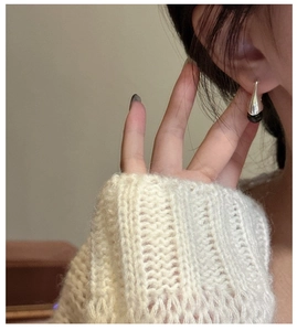 Detail view of water drop S925 silver earrings with black onyx on model with knit sweater