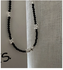 Gros plan détaillé des perles en argent S925 et des pierres d'agate noire sur le collier
