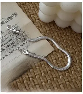 Détail du bracelet chaîne serpent en argent 925 sur des pages de livre vintage