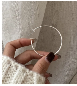 Gros plan de grande créole en argent sterling 925 tenue à la main avec fermoir fleur élégant