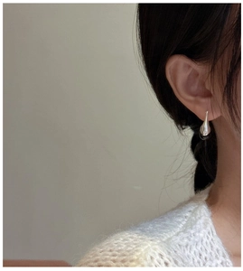 Close-up of minimalist silver water drop earrings on model for a trendy aesthetic look