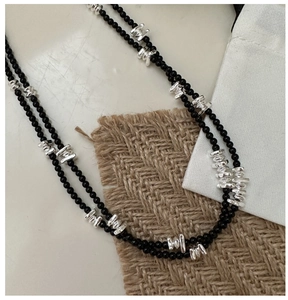Vue macro de perles en argent S925 et pierres d'onyx noir sur un collier au style minimaliste