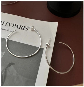 Gros plan de créoles en argent sterling 925 avec base pétale sur un magazine vintage