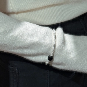 Bracelet perlé minimaliste en argent S925 avec agate noire sur un pull blanc
