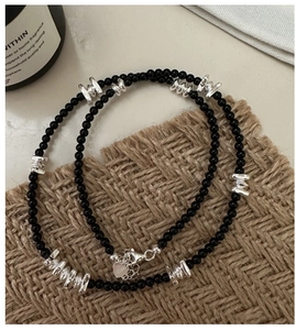 Gros plan du pendentif en argent S925 et des perles d'agate noire du collier