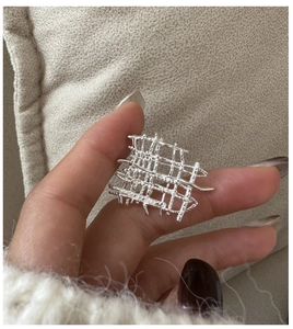 Vue rapprochée d'une bague tressée en argent avec texture géométrique irrégulière style industriel