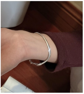 Détail d'un bracelet minimaliste en argent porté sur un poignet féminin