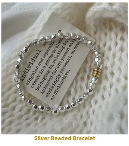 Detail of silver irregular bead bracelet with gold rings on white knit background