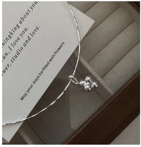 Detail of silver S925 necklace showing textured chain and four-bead clover pendant