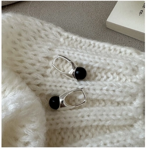 Close-up of S925 silver ear hoops with black onyx beads on white knitted fabric