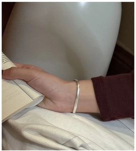 Gros plan d'un bracelet en chaîne serpent plate argentée porté au poignet d'une femme