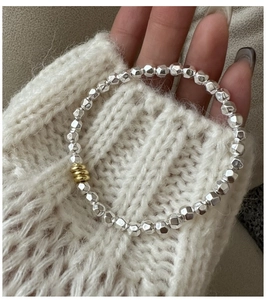 Detail of S925 silver beaded bracelet with gold accents on knit sweater background