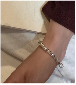 Macro shot of S925 silver faceted geometric beads bracelet worn on wrist with metallic texture